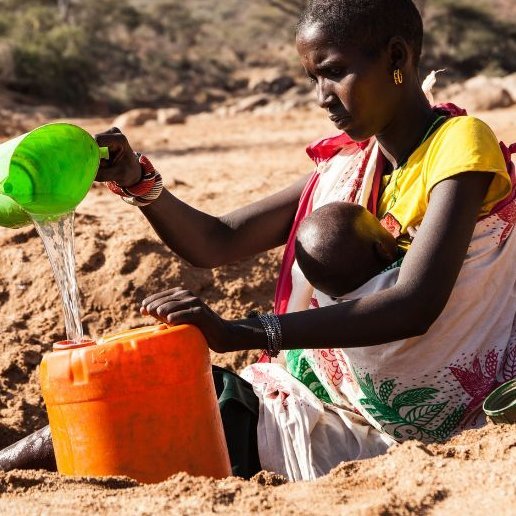 Frau mit Baby an vertrockneter Wasserstelle in Kenia