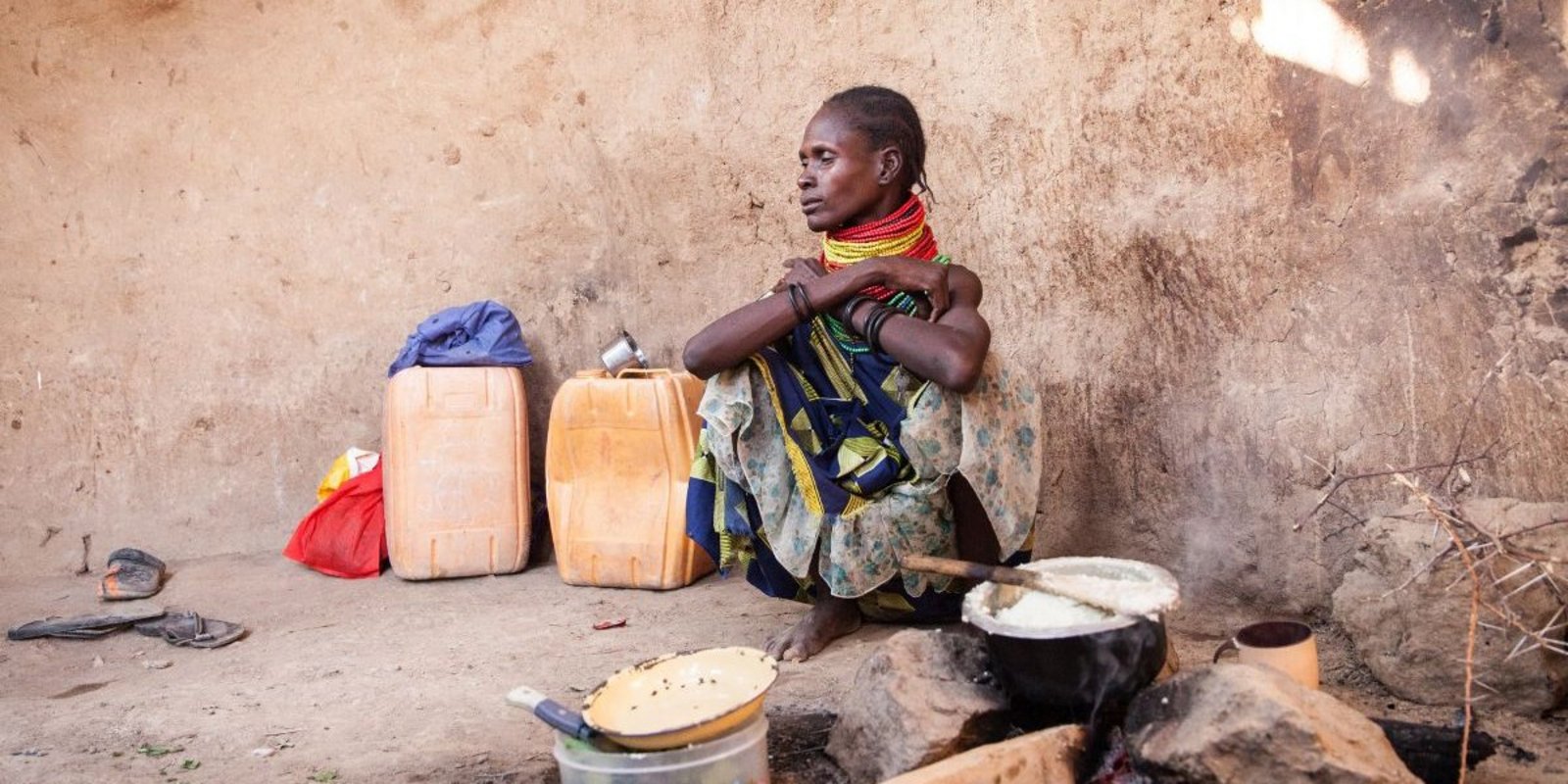 Kenianische Frau kocht Maisbrei auf Drei-Stein-Feuer